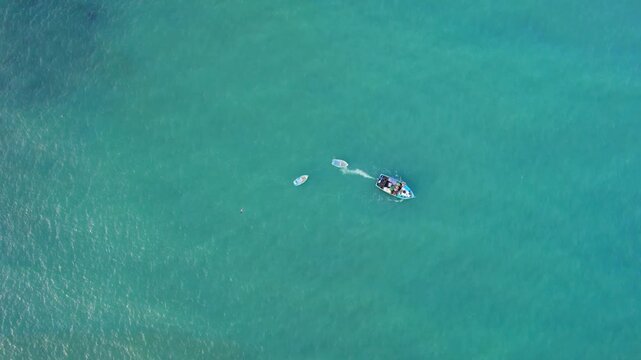 Aerial view of a small boat floating in the clear turquoise waters of the Pacific Ocean near Lima, Callao Region, Peru.