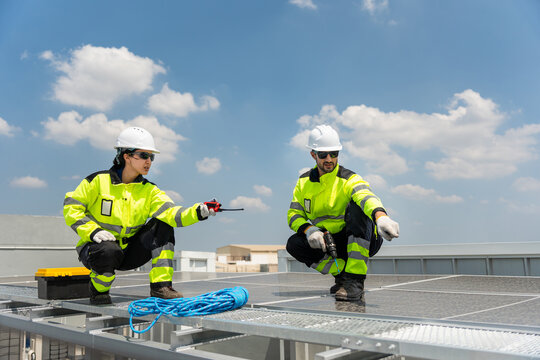 Professional solar technicians inspecting rooftop solar panel installation, Team of renewable energy engineers working together on a solar power rooftop array