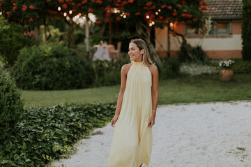 Fototapeta premium Woman in a flowing yellow dress strolls in a serene garden setting