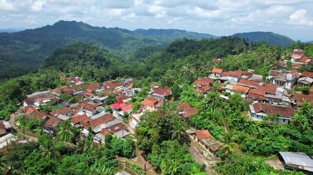 Aerial drone footage of a hidden local village in the middle of a valley, in Bruno area, Purworejo regency, Java island area, Indonesia, with forest around