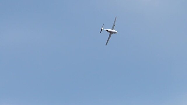 Small airplane flying over blue sky.