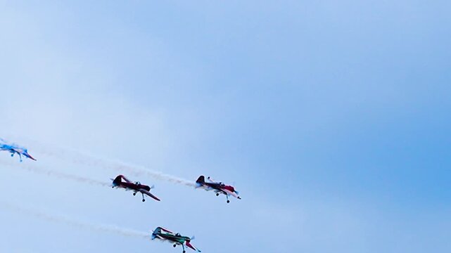 Sports planes fly in formation with smoke trails.