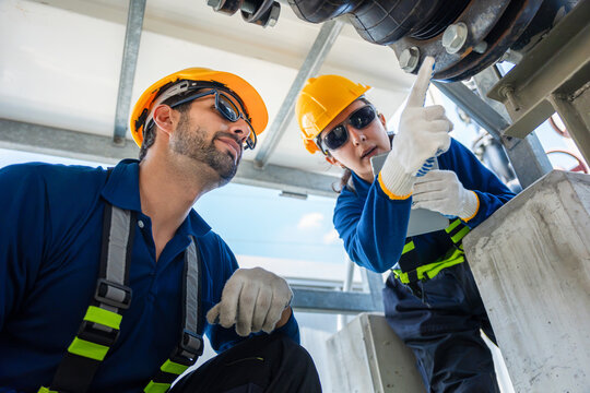 Industrial engineers inspecting piping system components in a manufacturing plant, Technicians with tablet to check pipeline maintenance and safety, Worker team monitoring industrial pipe connection