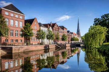 Obraz premium A tranquil canal with brick houses and reflections in Oldenburg.