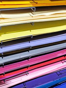 Stacks of colorful felt fabric sheets, paper in orange, red, green, brown, and blue on a metal shelf. Craft materials displayed in a store, ideal for art and DIY projects.
