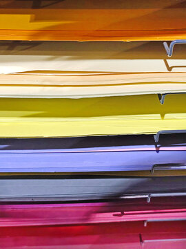 Stacks of colorful felt fabric sheets, paper in orange, red, green, brown, and blue on a metal shelf. Craft materials displayed in a store, ideal for art and DIY projects.
