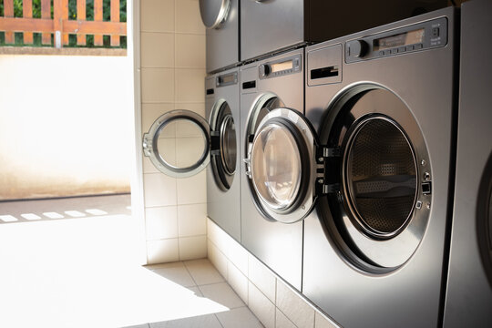 Several washing machines and tumble dryers in a campground laundry room. Self-service laundry facilities available for campers, featuring modern appliances in a clean and organized shared washing area
