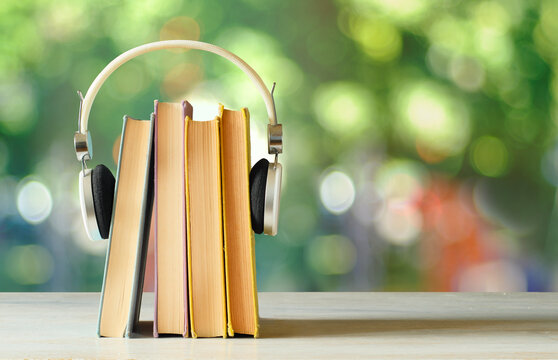 audiobooks concept with  stack of books and headphones on blurred nature background,free copy space