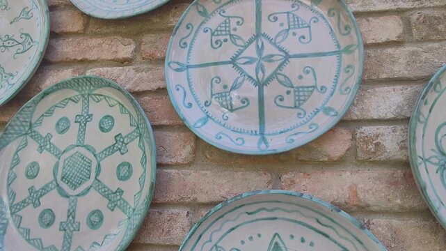 Decorative ceramic plates with intricate patterns hanging on a brick wall.