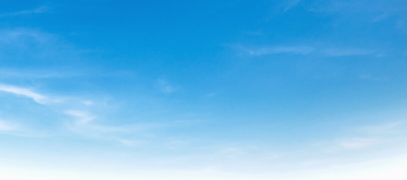 Calm sky stretches wide with soft, wispy clouds