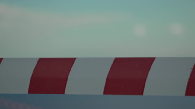 Barrier, Stripes, Red. Abstract moving striped barrier pole across blurred sky background, close up