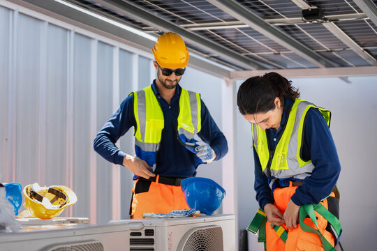 Technicians preparing safety gear for solar power system maintenance, Solar energy team putting on protective equipment, Workers in high visibility clothing preparing for inspection of solar panels