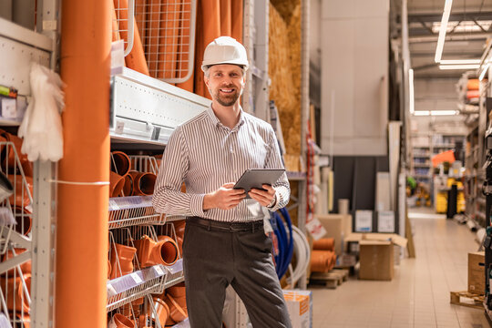 warehouse employee studies goods in a hardware store and checks the availability of goods on a digital tablet.