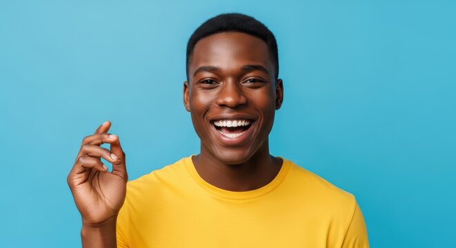 Happy Young African American Man Snapping Fingers and Smiling Broadly Against Blue Background