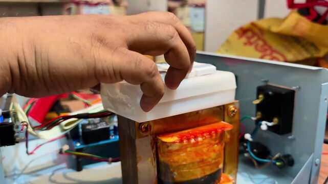 Technician Pressing Switch on Custom Inverter Circuit with Copper Transformer