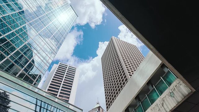 A low-angle shot from below captures the towering modern skyscrapers in Hong Kong's Central district