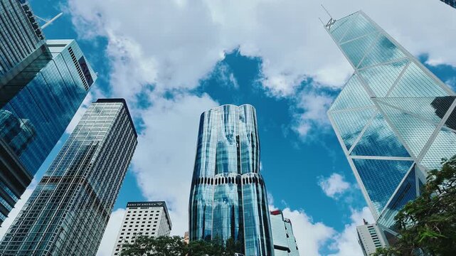 A low-angle shot from the ground level looking up at a modern cityscape of Hong Kong's Central district