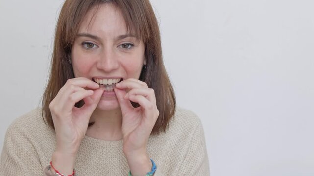 adult woman removing a transparent plastic aligner for teeth correction and dental care. Orthodontic treatment with removable braces for a beautiful smile, isolated on a white background