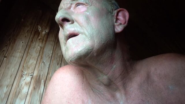 Stockholm, Sweden A man applies a mud mask to his face in a sauna.