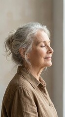 Fototapeta premium Elderly woman with grey hair closed eyes smiling peacefully. Calm meditative mood reflecting inner peace and aging grace. Use for wellness, healthcare or retirement lifestyle content.