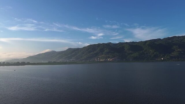 Vast Lake With Lush Green Mountains Under Blue Sky