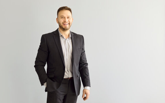 Businessman portrait smiling, professional male man in suit. Confident corporate executive on gray background with copy space for advertising or recruitment. Clear message of business success.