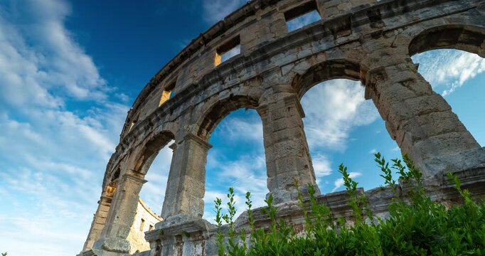 Time lapse of rushing clouds over the ancient Roman Pula Arena amphitheater architecture in Croatia with low angle view during bright day