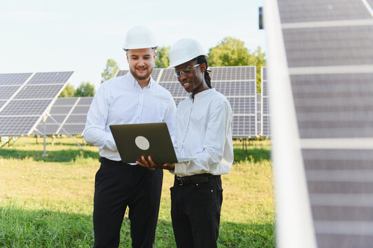 Engineers collaborating on solar panel field using laptop