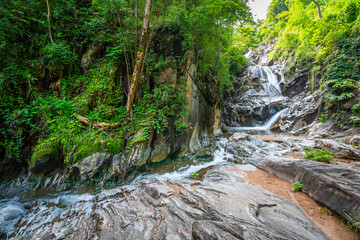 Lan Sang Waterfall cascades down massive rocky cliffs into a beautiful mountain stream in Tak, Thailand. Lush green jungle trees and mossy canyons surround this serene, wild wilderness paradise. © Around Ball