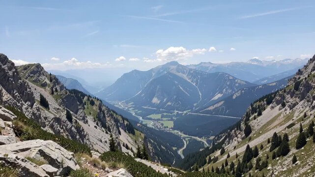 Spectacular mountain range under clear blue sky with patchy clouds.