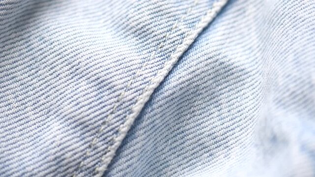 Blue denim cotton jeans fabric texture, jean background, textile backdrop, top view. wallpaper, blue jean fabric close up. Rotating, slow motion 
