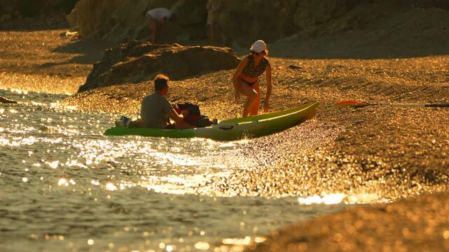 Kayaking kayak sunset couple preparing a sea kayak for an evening adventure on a rocky Mediterranean beach during the golden hour