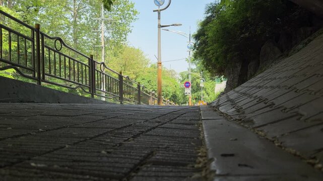 View from a concrete bridge underpass looking out towards a sunny suburban street with safety fences