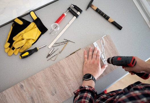 Worker drilling metal bracket into wood board