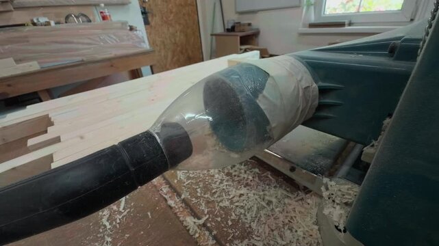 Close Up Handheld Shot Of Improvised Dust Extraction Vacuum System Processing Wood Shavings On Heavy Thickness Planer Machinery Inside Local Manufacturing Carpentry Workshop Environment During Workday