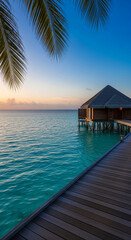 Fototapeta premium Ocean bungalow on stilts over turquoise water at sunset, framed by palm fronds, symbolizing tropical paradise and tranquil escape