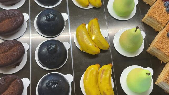 desserts in the form of a pear, banana in a showcase, cakes, also desserts in the form of currants, blueberries and coffee beans, also in the form of strawberries, such expensive desserts.