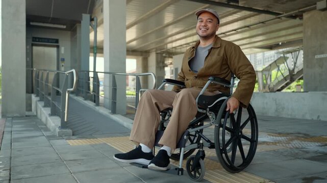 Happy disabled man using a wheelchair independently on a accessible city sidewalk with wheelchair ramps. Barrier-free infrastructure. Equal access, smart city, disability rights and mobility.
