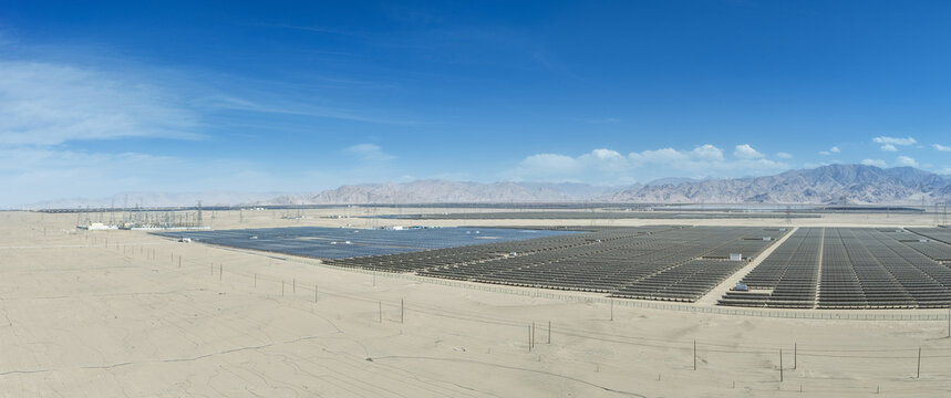 Expansive Desert Solar Farm with Transmission Infrastructure Under Clear Blue Sky