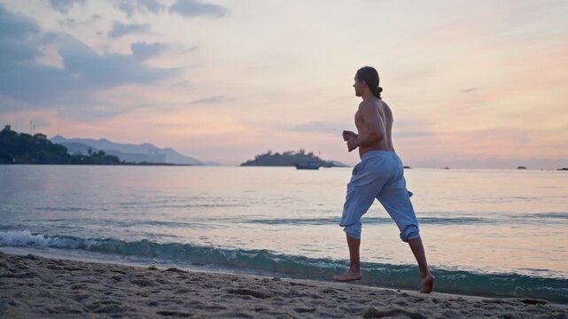 Man jogging along a sandy beach at sunset with calm sea and pastel sky