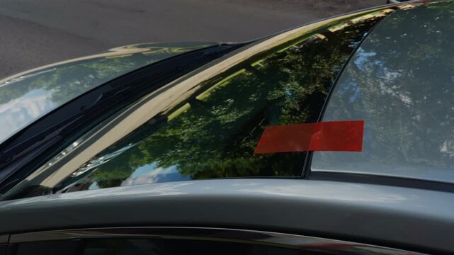 Close-up of car windshield with red tape marking visible damage and reflective glass surface