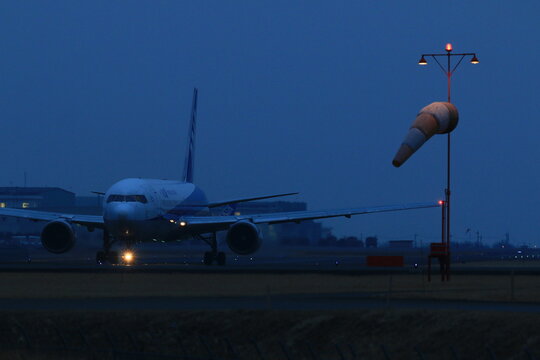All Nippon Airways (ANA) Boeing 787 on the taxiway at dusk beside a windsock on February 4, 2015 in Aso Kumamoto Airport, Japan.