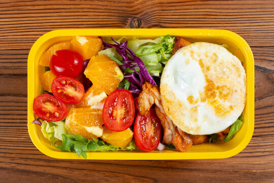 Fresh colorful salad with fried egg and glazed grilled meat and orange wedges and cherry tomatoes and mixed leafy greens