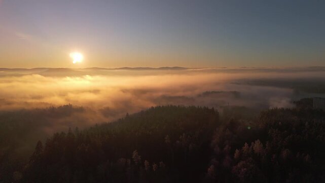 Aerial view of sea of fog over morning countryside under clear sky with sun