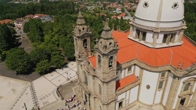 Aerial view of the Sanctuary of Our Lady of Sameiro with its distinctive dome and twin bell towers, surrounded by lush green trees and a paved plaza in Braga, Braga, Portugal.
