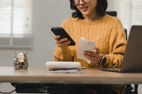 A woman scanning a paper receipt with her smartphone to track expenses in an office