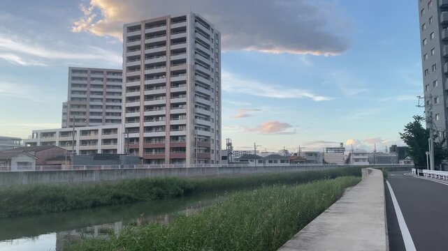 夕方の川沿いに佇む高層マンションと青空の風景