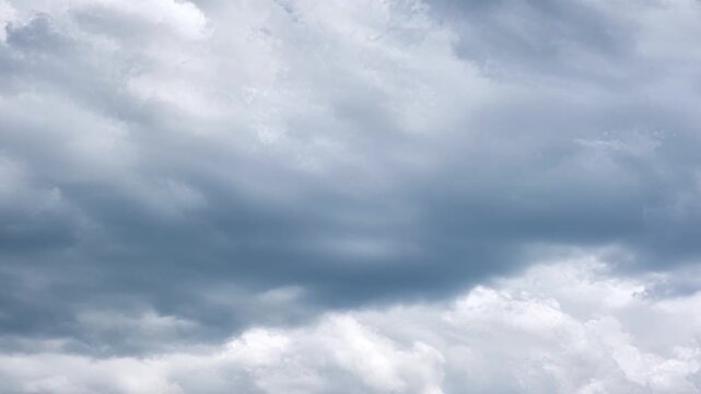 Towering cumulonimbus cloud bank shifting across blue sky with dramatic light, deep shadow, layered texture, wide horizonless backdrop, moody weather atmosphere