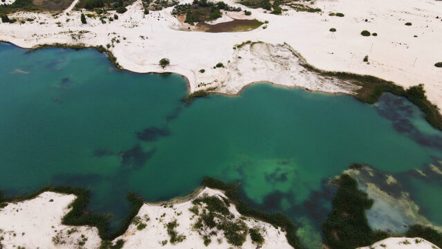 Emerald lake surrounded by white sand dunes, aerial view revealing calm water and natural oasis landscape