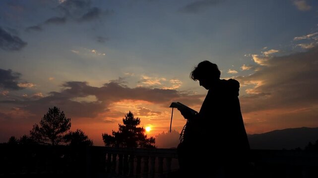 Silhouette of Person Reading Holy Bible Outdoors During Sunset During Quiet Christian Devotion
